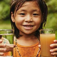 young child holding a glass of orange juice